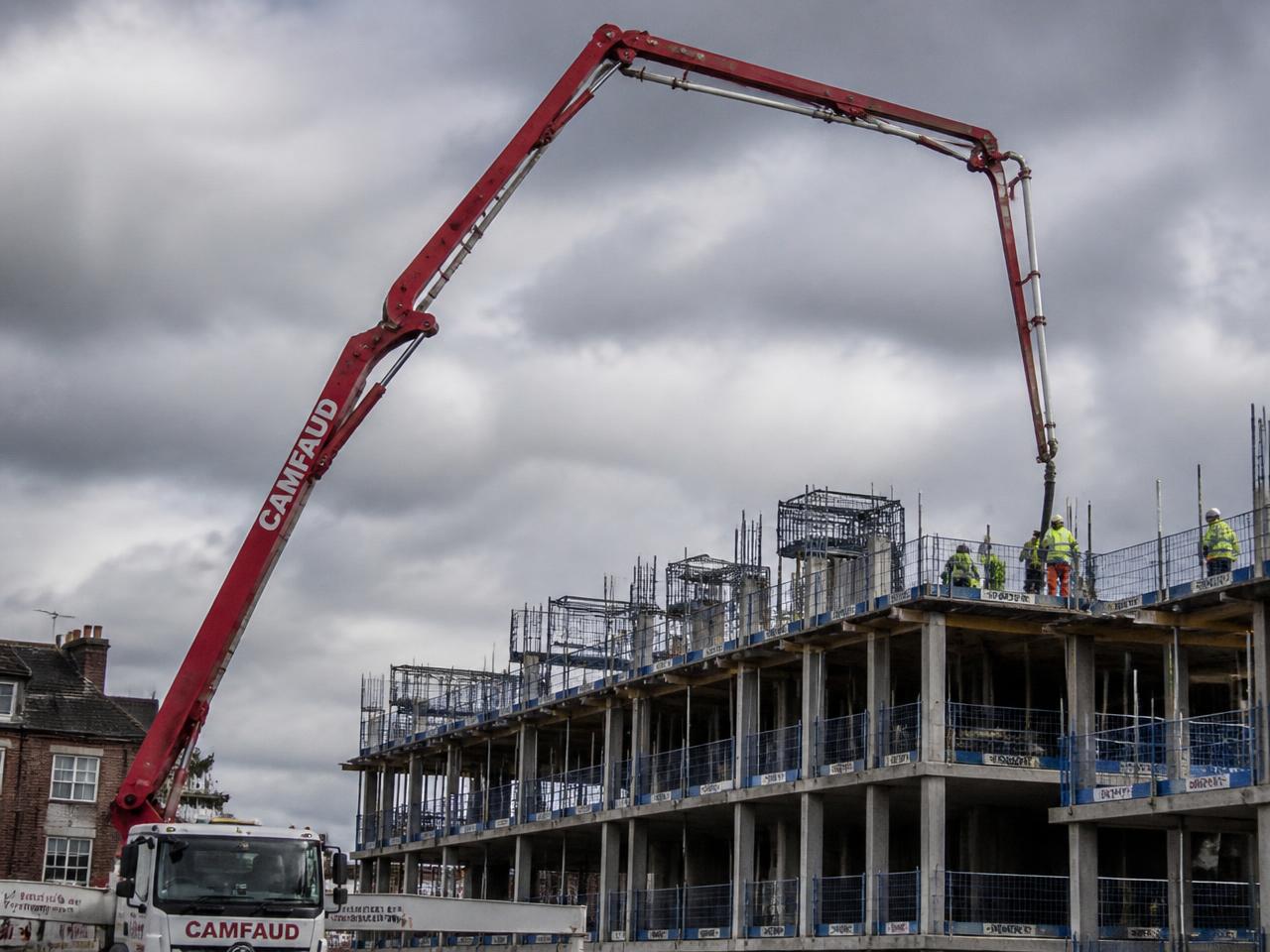 Concrete boom pump reaching over a multi-storey building