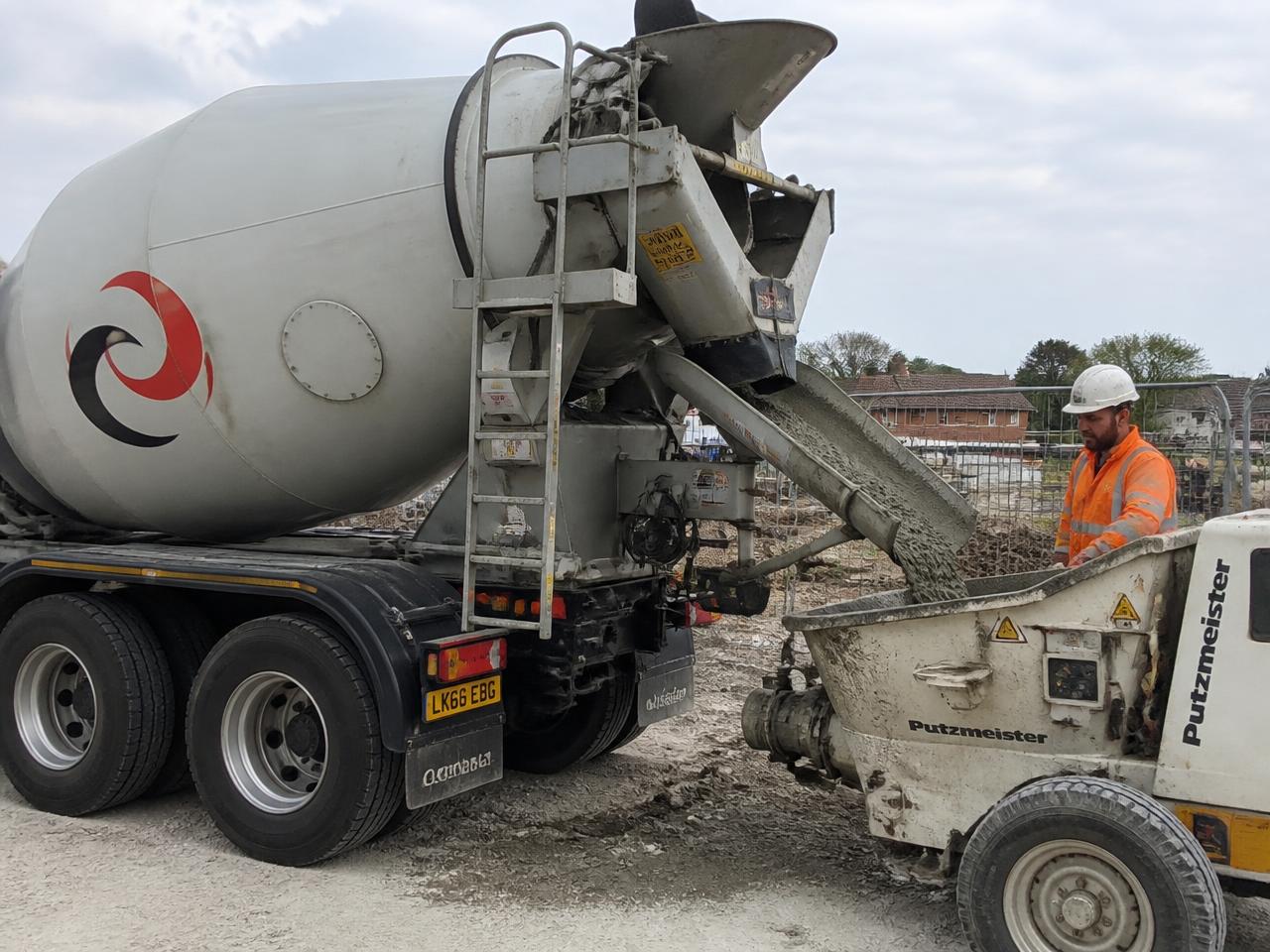 Readymix concrete mixer truck discharging into a concrete pump hopper